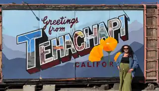 Laura beside the Greetings from Tehachapi mural.