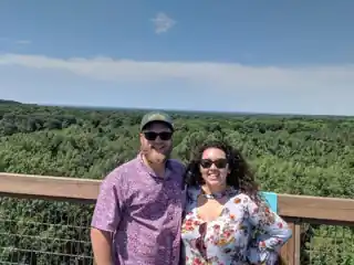Laura and Bryce on an overlook above a green forest.