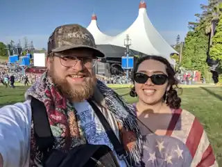 Laura and Bryce on a concert lawn in front of white tents.