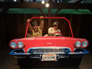 Laura and Bryce in the red LA County Fair car, resting on rubber tires.