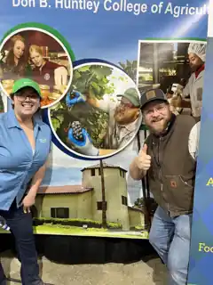 Laura and Bryce beside a Cal Poly Pomona College of Agriculture display featuring Bryce.
