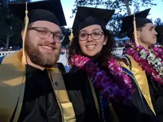 Laura and Bryce celebrating graduation in caps and gowns.